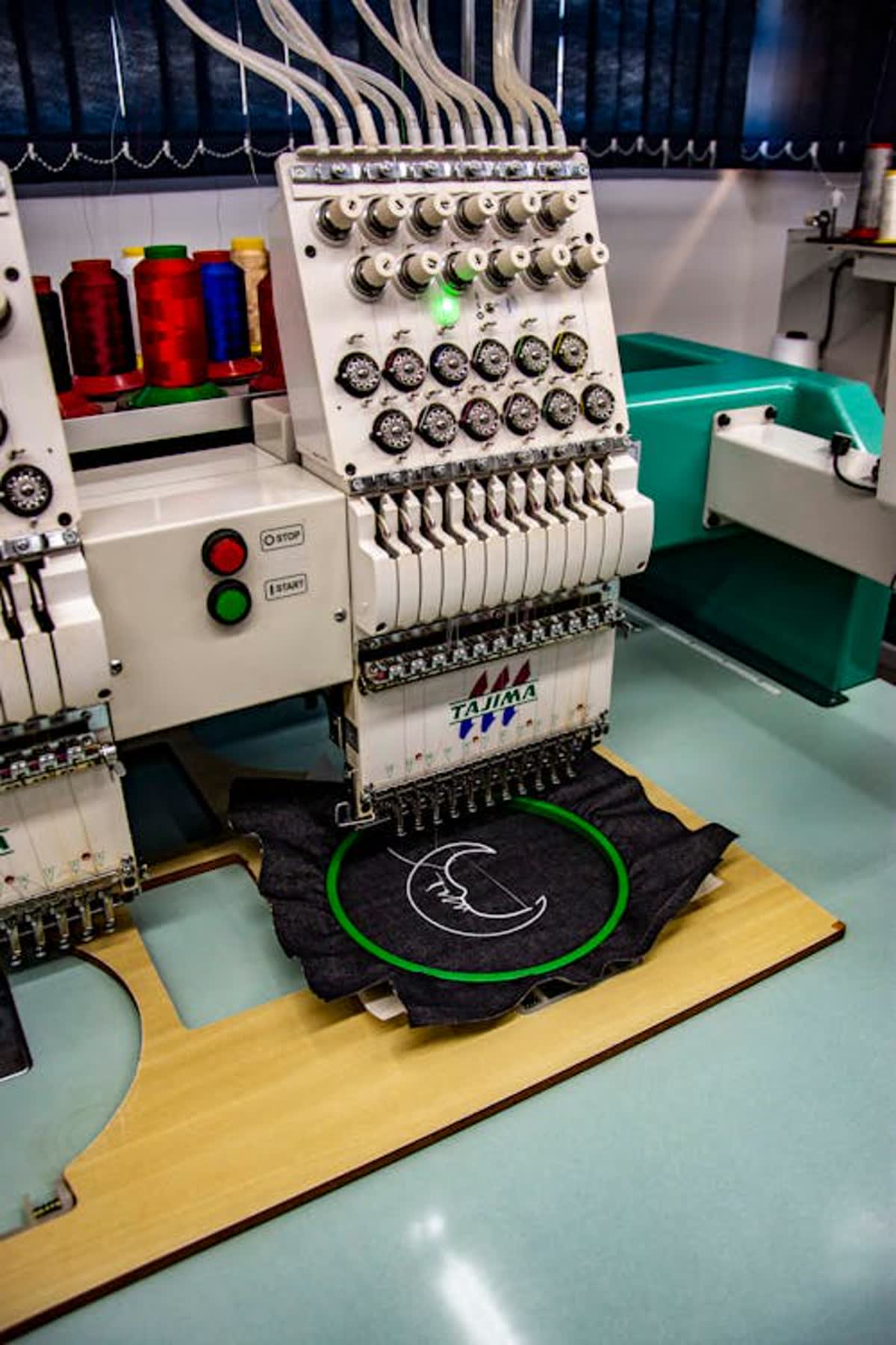 Máquina bordadora con hilos de colores aplicando un emblema
